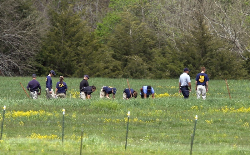 Law enforcement officials scan the fields behind a farm Thursday, May 9, 2013 in search of an 18-month-old baby in rural Ottawa, Kan., where three bodies were found on Monday. Authorities in eastern Kansas said Thursday they have arrested a 27-year-old suspect in the deaths of three people whose bodies were found at a farm, and that a fourth victim — an 18-month-old girl — was found Sunday, May 12, 2013. (AP Photo/The Topeka Capital Journal, Chris Neal)