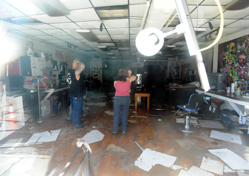 Mona Juliano, center facing, co-owner of Ink-4-Life, receives a hug from a tenant in a Main Street building in downtown Waterville, which was destroyed by a fire Friday afternoon, as they clean up their shop Saturday morning.