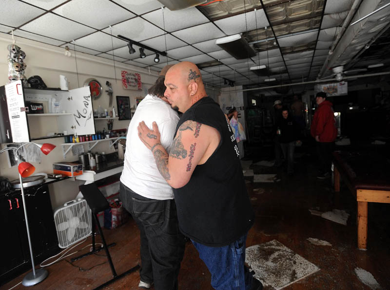 Bill Juliano, right, receives a hug from friend Shane Lake, in the Ink-4-Life on Main Street in downtown Waterville Saturday morning. The tattoo studio, along with three floors of apartments above, were destroyed Friday by fire.