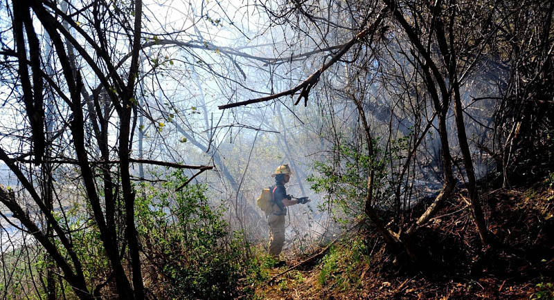 Capt. Kevin Fredette of the Winslow Fire Department battles a blaze in the hills behind Dallaire Street, near the Kennebec River, in Winslow Saturday afternoon.