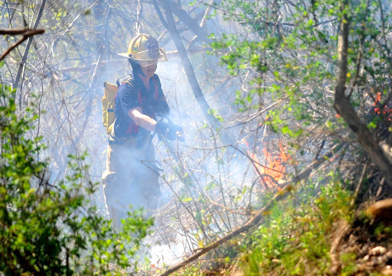Capt. Kevin Fredette of the Winslow Fire Department battles a blaze in the hills behind Dallaire Street, near the Kennebec River, in Winslow Saturday afternoon.