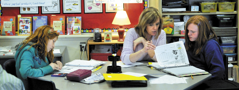 Karen Mayo, a fifth-grade teacher at the James H. Bean School in Sidney, helps two students, Jade Veillaux, 11, right, and Macey Eubank, 10, left, on Wednesday. James H. Bean is one school in the area that has implemented a mass customized learning program, which integrates up to three grade levels in one classroom.