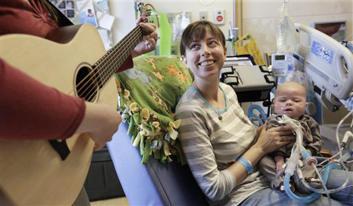 Music therapist Elizabeth Klinger, left, quietly plays guitar and sings for Henry Buchert and his mother Stacy Bjorkman, in the Pediatric Intensive Care unit at Ann & Robert H. Lurie Children's Hospital in Chicago.