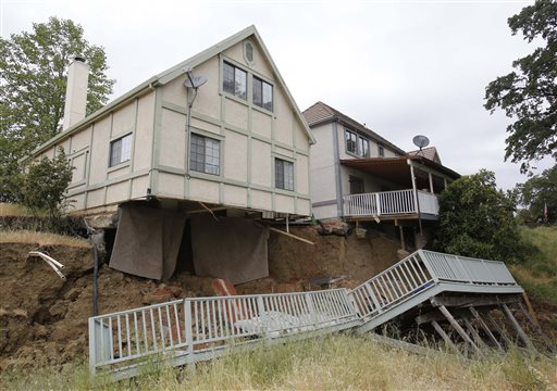 The bedroom carpets hang from the home of Jagtar Singh, left,on May 6 after the ground gave way in Lakeport, Calif. Shortly after Singh moved his wife, 4-year-old daughter and his parents to the subdivision, the hill behind his home collapsed taking the underside of his house.