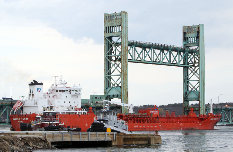 The 473-foot Harbour Feature rests against the Sarah Mildred Long Bridge on April 1 in Portsmouth, N.H. The estimate of the cost to repair the bridge has been lowered.