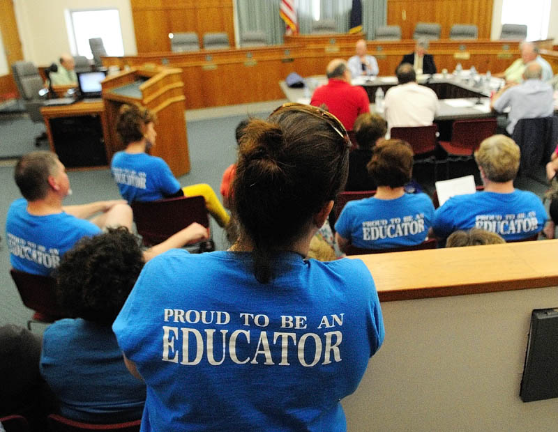Several people wearing blue Augusta Education Association T-shirts attend a standing room only city council budget wrap-up meeting on Thursday in Augusta City Center.
