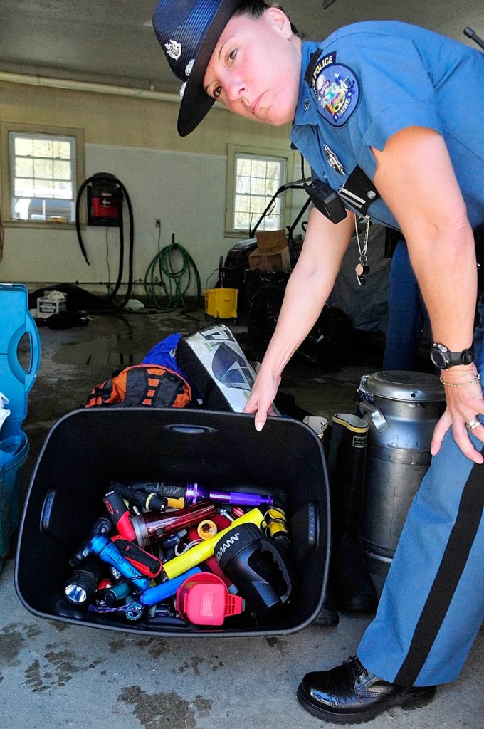 Trooper Diane Perkins-Vance shows a bin of flashlights recovered from the campsite of the North Pond Hermit, Christopher Knight, during an event at the Maine State Police Troop C barracks on Saturday in Skowhegan.