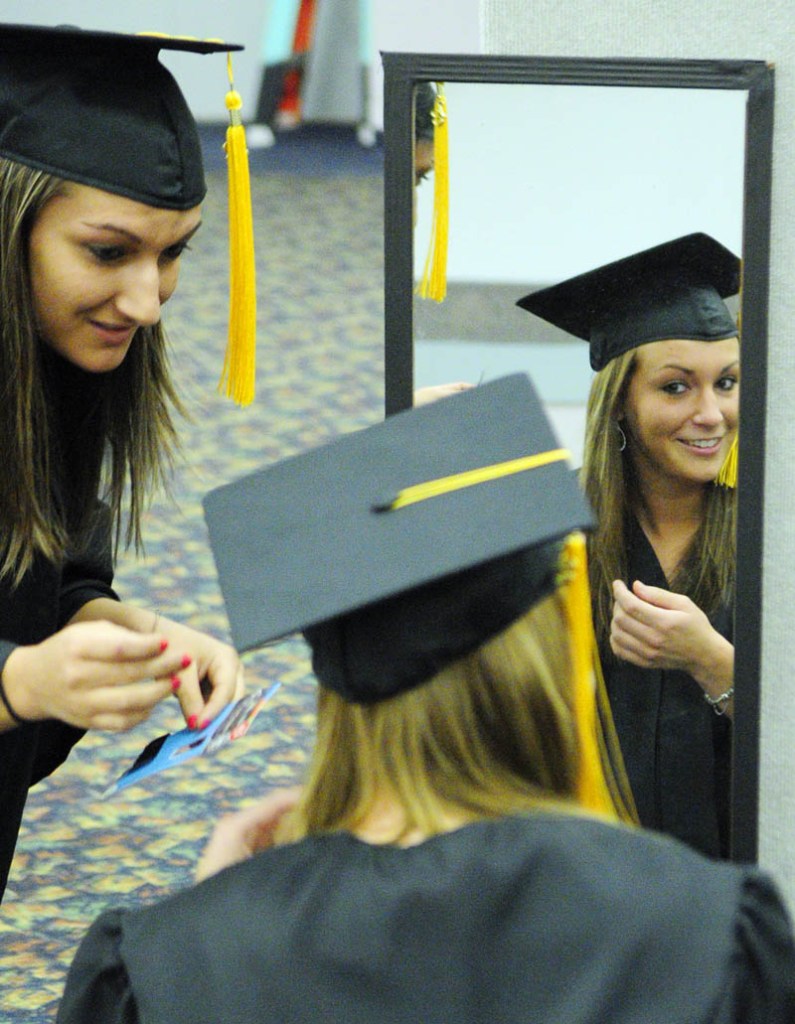 Brittany Bouchard, left, of Waterville, helps classmate Chelsi Brewer, of Skowhegan, adjust her mortarboard before the Kennebec Valley Community College commencement on Saturday at the Augusta Civic Center.