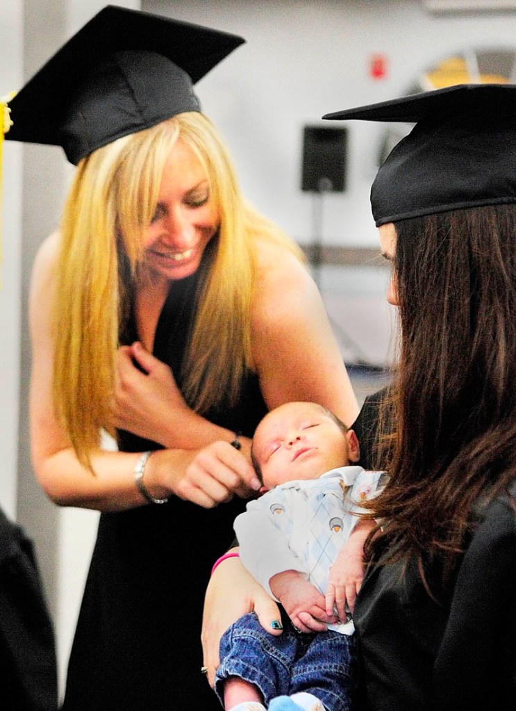 Jackie Wolinski, of Smithfield, left, meets Lliam Kimball, the 3-week-old son of fellow occupational therapy assistant graduate Brandy Kimball, of Liberty, before the Kennebec Valley Community College commencement on Saturday at the Augusta Civic Center.