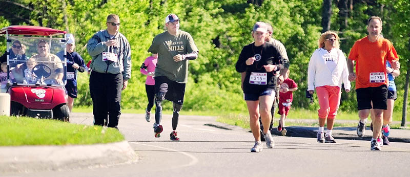 Staff Sgt. Travis Mills, center, talks to passing runners as he walks part of the course at the second annual Miles For Mills 5k on Monday at Cony High School in Augusta.