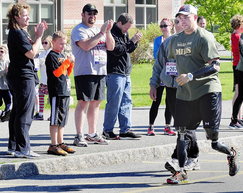 Spectators clap for Staff Sgt. Travis Mills as he heads to the finish line at the second annual Miles For Mills 5k on Monday at Cony High School in Augusta. Mills walked part of the course.