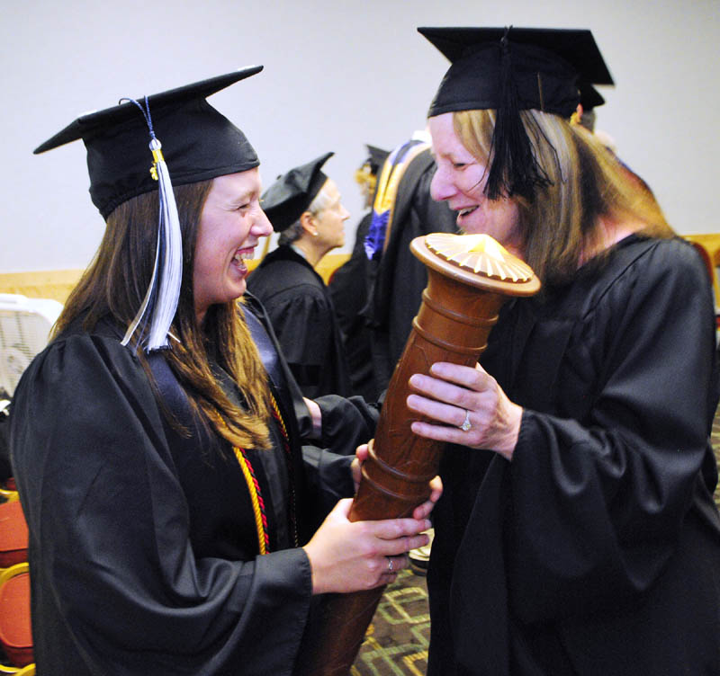Landon Hixon, left, chats with Ellen Schneiter, vice president of finance and administration, about the mace Hixon will carry in the ceremony before University of Maine at Augusta graduation Saturday.