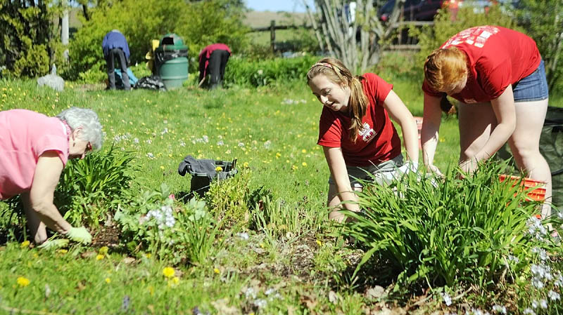 Nancy Voisine, left, and Cony High students Christina Claudel and Rebecca Coniff clean up a flower bed on Thursday at the Kennebec Valley Garden Club park in Augusta.