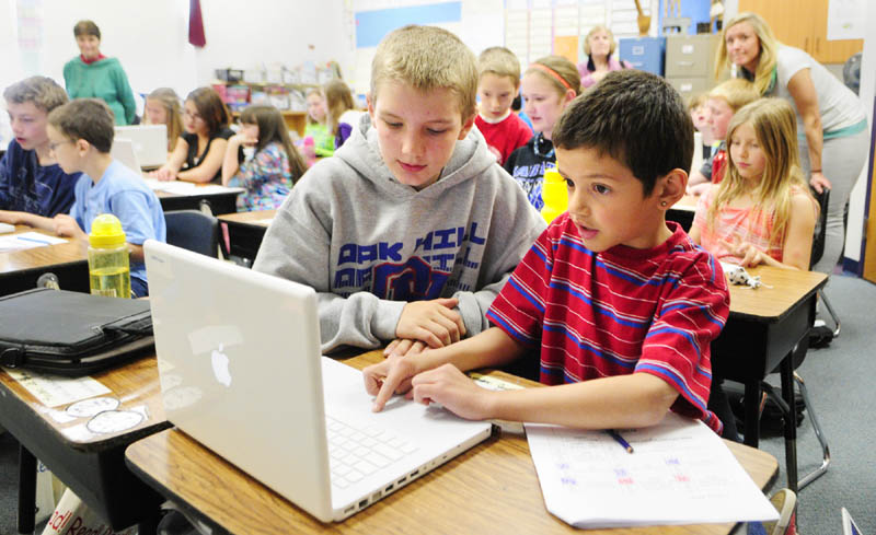Oak Hill Middle School seventh-grader Eric O'Connor, left, works with Carrie Ricker School third-grader on a MacBook on May 14 in Litchfield. Gov. Paul LePage sought to eliminate Maine's middle-school laptop program, according to emails received by MaineToday Media, but was persuaded against that move by Education Commissioner Stephen Bowen.