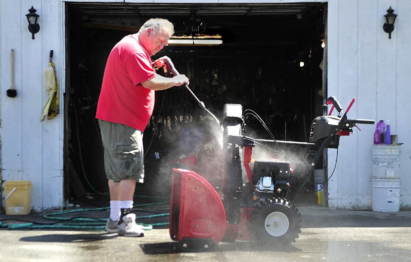 Roger Badershall power washes a snowblower on Tuesday in Augusta. He joked that it was probably safe to put it away for the season now.