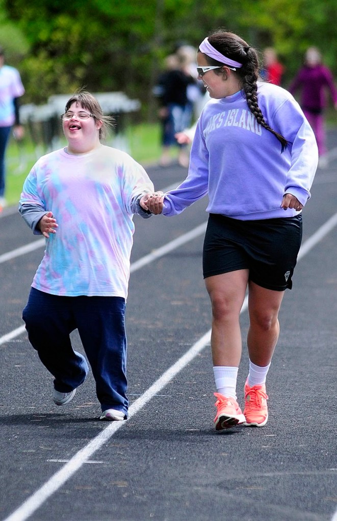 Messalonskee athlete Caitlin Douin and volunteer Natalie Hunt run the 100 meters event during the Kennebec Area Special Olympics Games on Tuesday at Hall-Dale High School in Farmingdale.