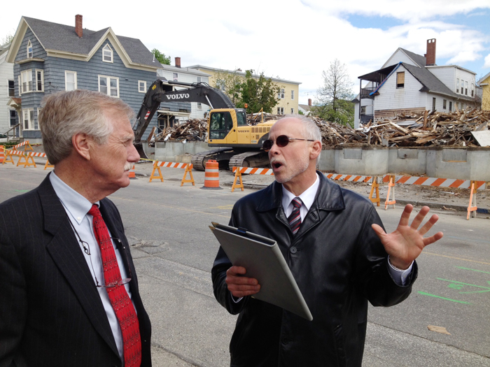 U.S. Sen. Angus King speaks with Assistant City Administrator Phil Nadeau in Lewiston as demolition work takes place on a building at 114-118 Bartlett St., which burned on May 6.