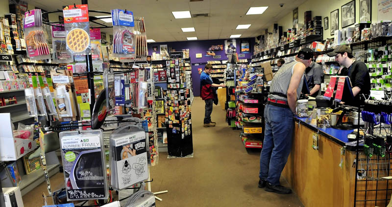 Bull Moose Music head clerk Aaron Beckim, right, waits on customer Arthur Ellis at the store in the Elm Plaza in Waterville. The business is expanding into the adjacent, former Mr. Paperback location.