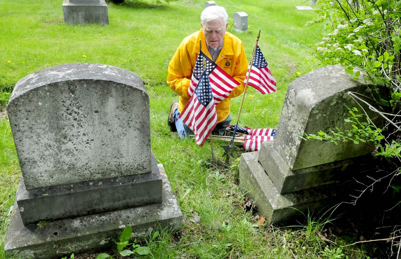 Veteran Burns Hillman places American flags near the grave of a Civil War Medal of Honor recipient buried at the Pine Grove cemetery in Waterville on Thursday. Hillman has decorated graves for close to 50 years.