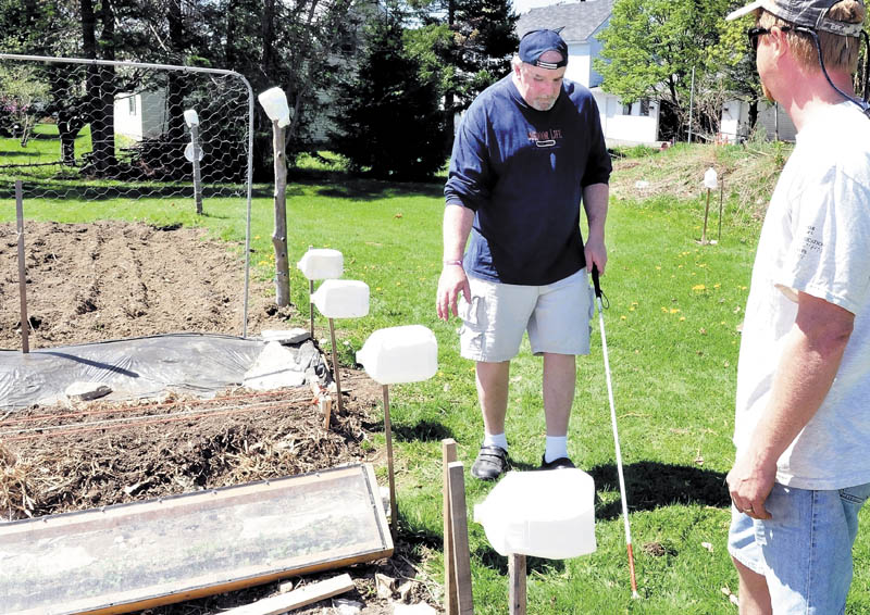 Gardener David Perry, right, watches as Deon Lyons negotiates through a vegetable garden in Fairfield that uses milk jugs and other markers to help visually impaired people work in the garden.