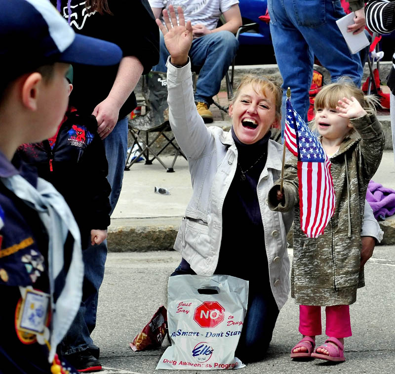 Kimberly Brooks and her niece, Mackenzie Gifford ,wave hands and flags at Memorial Day parade participants in Waterville on Monday.