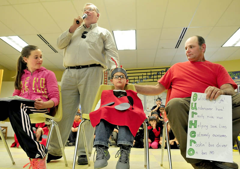 Regional School Unit 18 Transportation Director Lennie Goff, standing, acknowledges students Abby Whitcomb and Michael Remmers and bus driver Nathan Philbrick during an assembly at the James Bean School in Sidney on Tuesday. Whitcomb is credited with alerting Philbrick that Remmers was choking on candy recently allowing Philbrick to use his resuscitation training to assist.