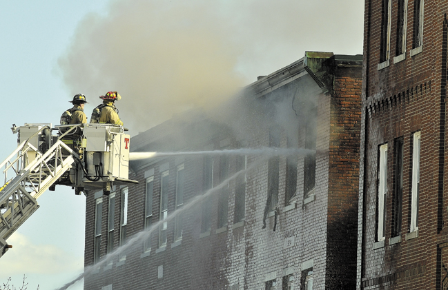 Waterville firefighters move in close to the top floors where flames were seen earlier Friday.