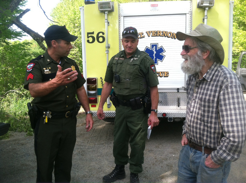 Warden Sgt Terry Hughes, left, and District Warden Dan Christiansen confer with Mark Hedden, 83, moments after he emerged from the woods near his Vienna home on Tuesday.