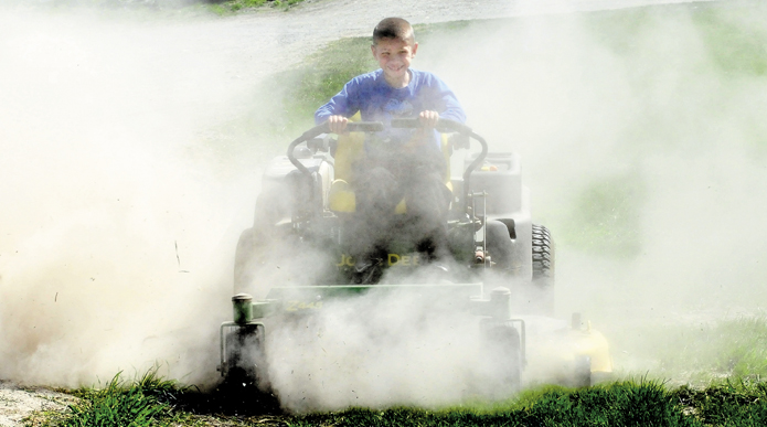 Egide Dostie kicks up a small dust storm while mowing the dry lawn at the family farm in Fairfield on Tuesday. More rain is on the way later this week to reduce fire danger.