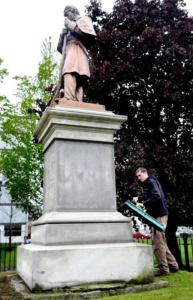 Nate Bernier of the Waterville Parks and Recreation Department brushes grass clippings off the Civil War monument in Veterans Park on Wednesday. The park will be site of Memorial Day events.