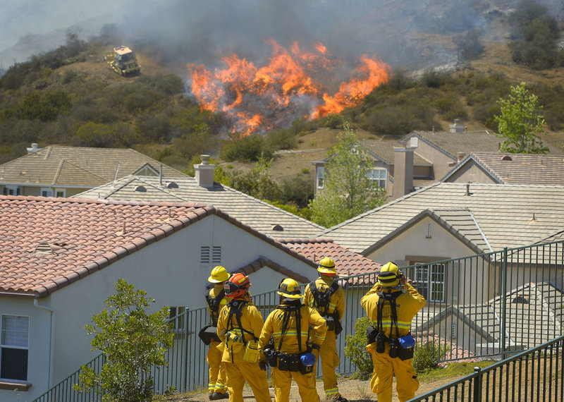 Firefighters from Glendale and Pasadena, Calif., stand watch as bulldozers clear a firebreak near a wildfire burning along a hillside near homes in Thousand Oaks, Calif., on Thursday.
