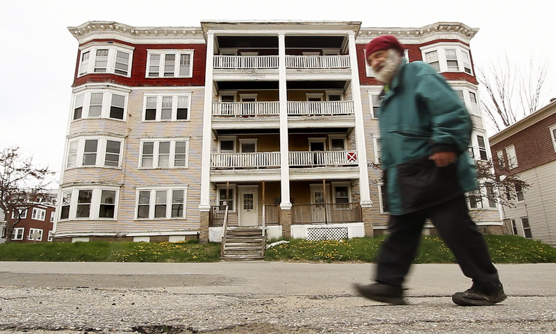 Roland Hamel of Lewiston walks past a condemned multi-unit dwelling on Walnut Street in a city where officials say abandoned buildings often hide in plain sight.