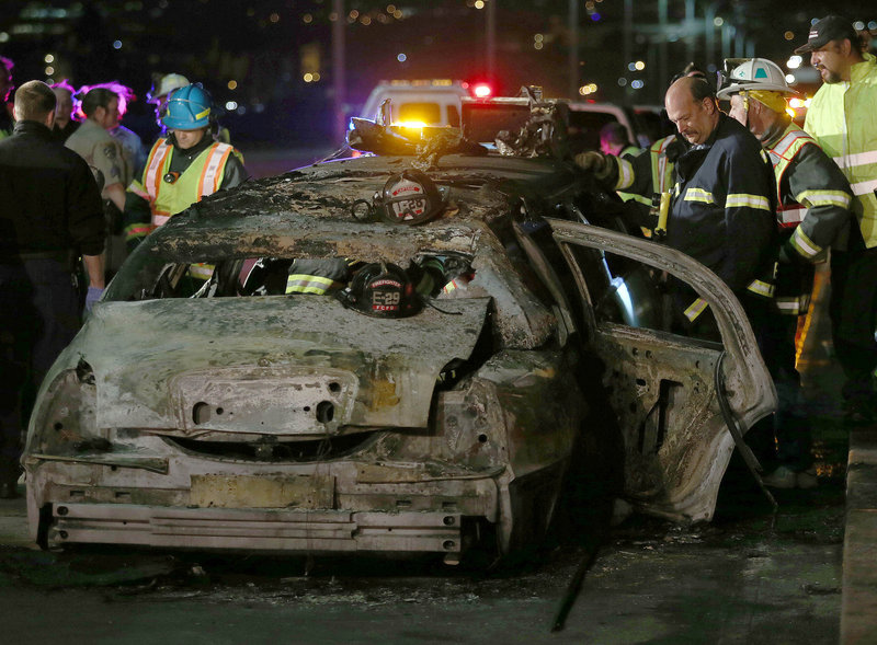 Officials investigate the scene of a limousine fire on the westbound side of the San Mateo-Hayward Bridge in Foster City, Calif., on Saturday night. Five people died when they were trapped in the limo; four others and the driver escaped.