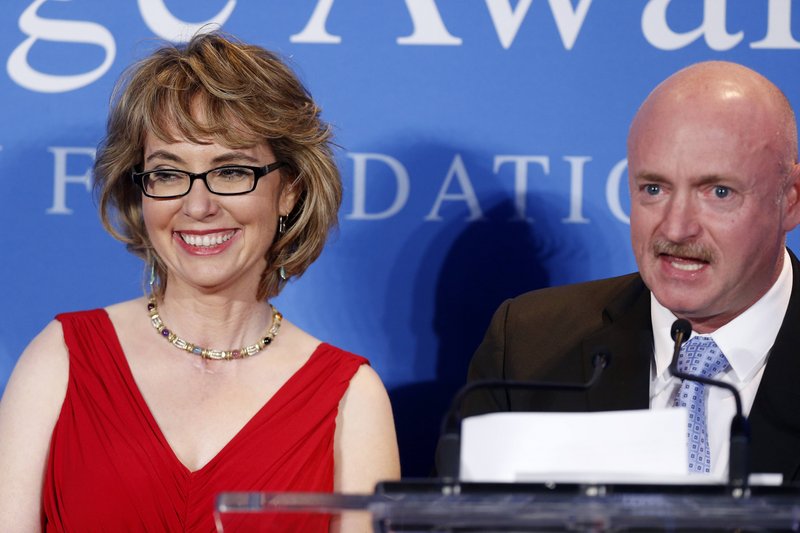 Mark Kelly speaks beside his wife, former Arizona U.S. Rep. Gabrielle Giffords, after Giffords received the John F. Kennedy Profile in Courage Award at the JFK Library in Boston on Sunday.