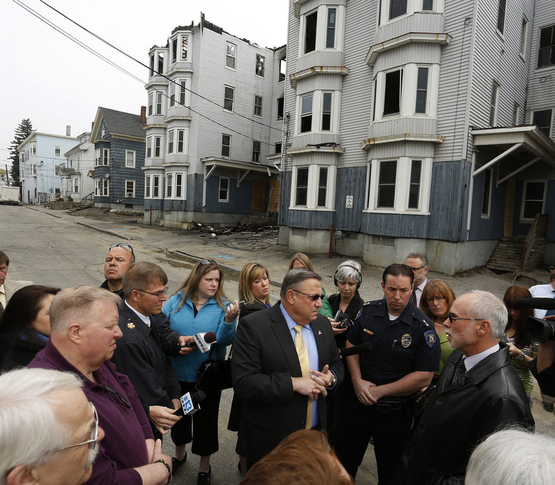 Gov. Paul LePage talks to the media Tuesday while meeting with Lewiston officials in front of two buildings that burned Monday on Bartlett Street. Asked if he was happy to be back in his hometown, where he was homeless as a youth for two years, he said, “It brings back a lot of bad memories.”