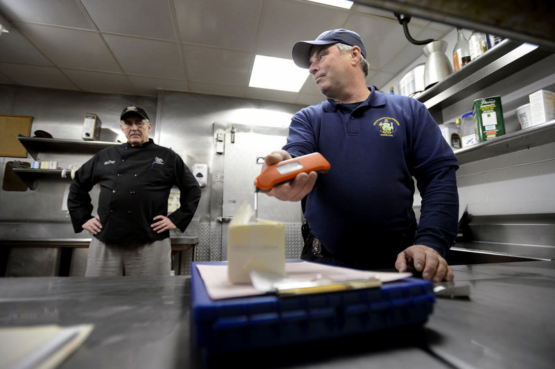 Scott Davis, a state health inspector, checks the temperature of food stored in a walk-in cooler in the kitchen at the Stage Neck Inn in York Harbor as executive chef Lynn Pressey looks on. “He knows we’re trying to do the right thing.” Pressey said.