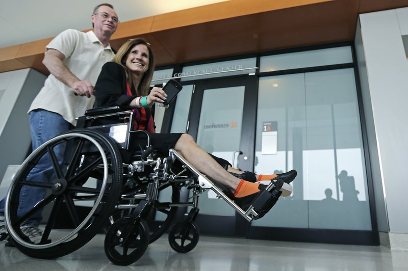 Boston Marathon explosion survivor Beth Roche, of Highland, Ind., is pushed through the hallway at the Spaulding Rehabilitation Hospital by her husband Ken Roche, in Boston, Tuesday, May 28, 2013. Roche said she is hoping to meet a man who helped her at the bombing scene, who she has yet to find, before her hospital discharge later this week. (AP Photo/Charles Krupa)