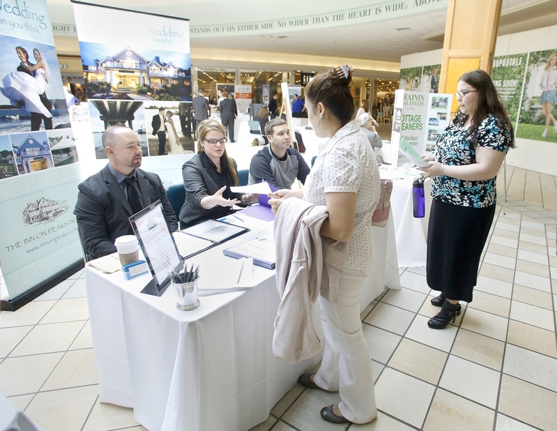 Ashley Dombrowik of Saco hands an application to Amanda Conley, event coordinator at The Inn on Peaks Island, during a job fair at the Maine Mall in April. Seated are Jayson Mathieu, the event manager, left, and Andrew Hobin, bar manager at The Inn on Peaks Island.