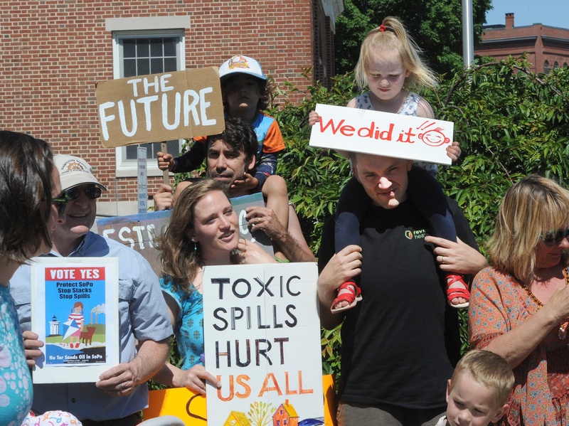 Two-year-old Cadence Kessler of South Portland sits atop her dad Chris Kessler, who stands next to her mother, Jessie Kessler, left, as they join members of the Concerned Citizens of South Portland at a news conference Monday. TarSands