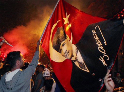 Turkish protesters, mostly soccer fans of Besiktas who call themselves "Carsi," wave a poster of Turkey's founder, Kemal Ataturk, as they celebrate in rain at the city's Kugulu Park in Ankara, Turkey, Saturday.