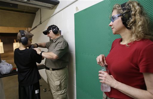 Cheryl Strain, right, watches as instructor Scott Stevens, center, shows her son Rory, 12, how to properly hold a shotgun at a shooting range in Houston on May 19. The Strains live in the first residential area being trained and equipped by a nonprofit that is giving away free shotguns to single women and neighborhoods with high crime rates.