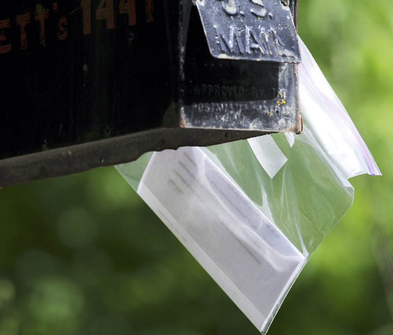 A letter enclosed in a plastic bag is attached to a Farmingdale mailbox Monday. Several people have reported receiving similar notes, that James Grant, a Board of Selectmen candidate, claims is forged with his signature.