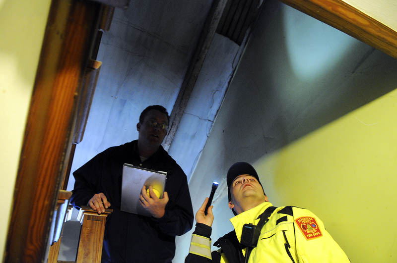 Augusta code enforcement officer Robert Overton, left, and firefighter Arthur True inspect an apartment in the city on Tuesday.