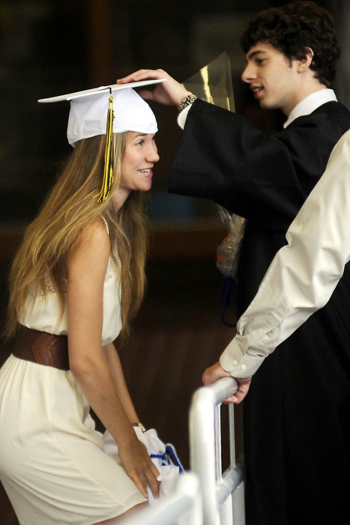 Maranacook Community High School senior Sydney Gilbert gets some assistance getting ready for graduation from her classmate, Richard Scheno, at the school in Readfield on Sunday.