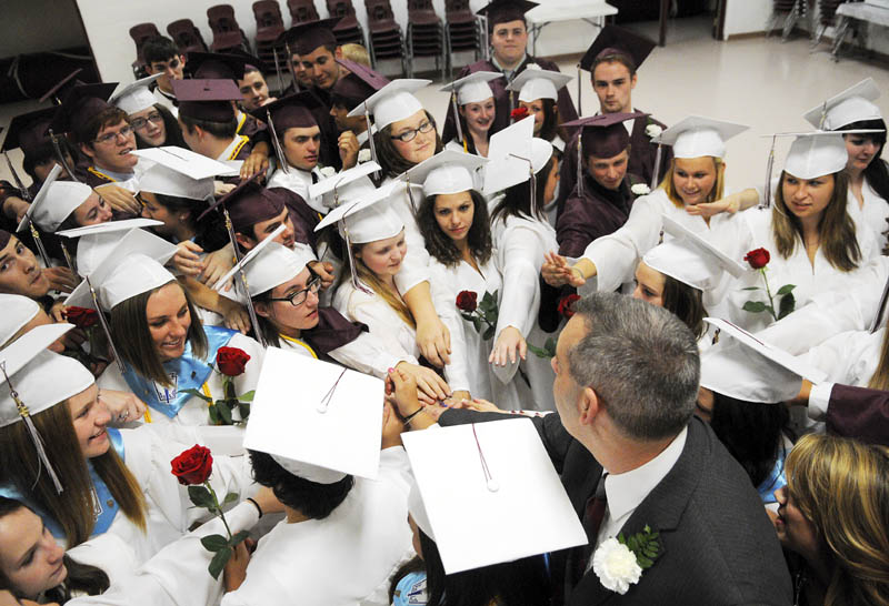 Monmouth Academy seniors surround principal Rick Amero for a group huddle before marching into graduation at the school on Sunday.