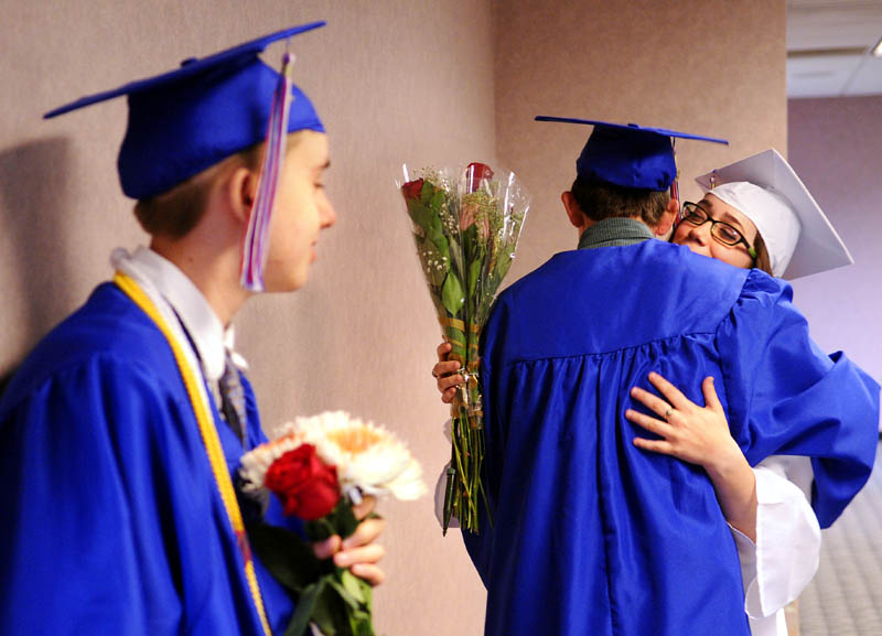 Oak Hill High School seniors Carina Weed, right, hugs Nic Ward while Isaac Fair, left, waits to march during commencement Monday at the Augusta Civic Center.