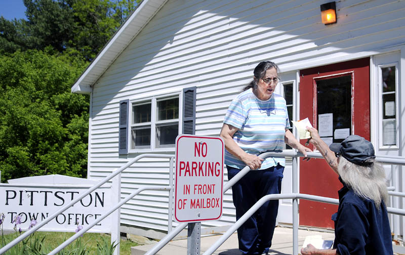 Pittston resident Dallas Price collects the registration he forgot at the counter at the Pittston Town Hall Wednesday, from town employee Mary Lawrence. The town has replaced three selectmen and Town Clerk Rose Webster is departing soon.