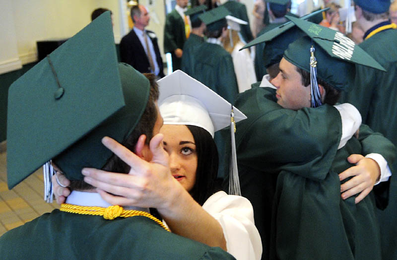 Peter Michelsen has his cap adjusted by classmate Aubree Ahearn as classmates Dalton Cummins, right, and Mitch Ketchen hug before Winthrop High School's commencement on Sunday.