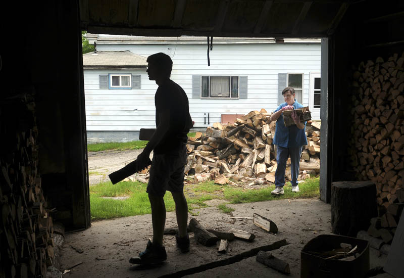 Zach O'Ben, left, stacks firewood with his grandmother, Pauline O'Ben, in the garage of her Gardiner home on Monday. The elder O'Ben said she dries the wood for a year before burning it, and the stacking goes much faster with the assistance of her grandson.