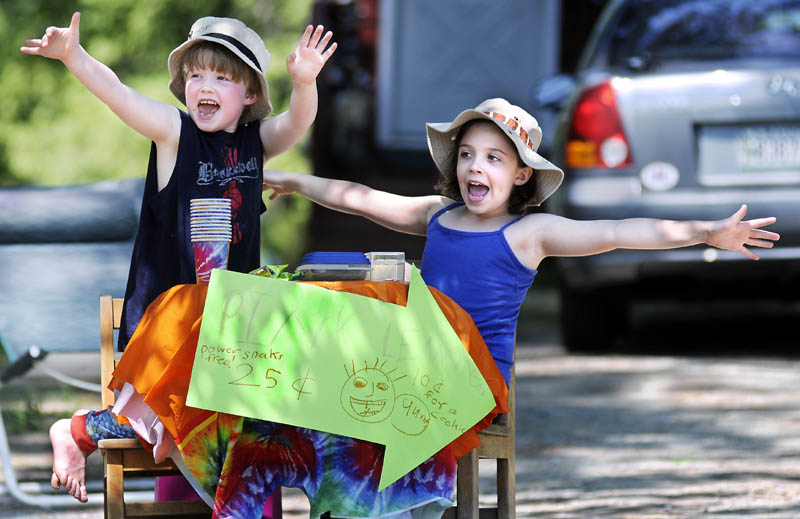 Sam Hayes, 5, and Emily Hayes, 8, solicit customers Sunday while selling lemonade and cookies along the road at their Mount Vernon home. The business plan was incubated in the kitchen, according to the elder Hayes child. "I saw lemonade mix in the kitchen and that gave me the idea," she said. Her brother plans to invest his share of profits in the purchase of a toy boat.